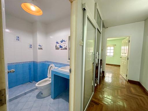 Bright bathroom with blue tile decor and wooden floor hallway