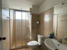 Compact tiled bathroom with glass shower enclosure, toilet, and sink