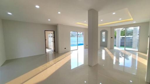 Spacious and brightly lit living room with reflective floor and swimming pool view