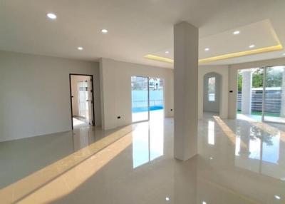 Spacious and brightly lit living room with reflective floor and swimming pool view