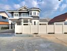 Modern two-story house with white walls and grey roofing under clear blue sky