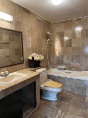 Spacious bathroom with marble tiles, a bathtub, and modern fixtures