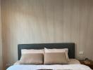 Modern bedroom with a neatly made bed, stylish headboard, and textured wallpaper
