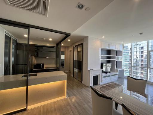 Modern apartment interior with open floor plan, including kitchen and living room, with ample lighting and city view