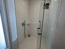 Modern glass shower enclosure with chrome fittings in a bright bathroom.