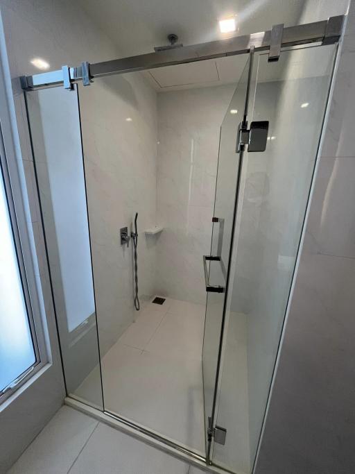 Modern glass shower enclosure with chrome fittings in a bright bathroom.