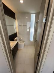 Modern bathroom interior with a white porcelain sink, toilet, and shower glass door