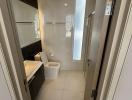 Modern bathroom interior with a white porcelain sink, toilet, and shower glass door