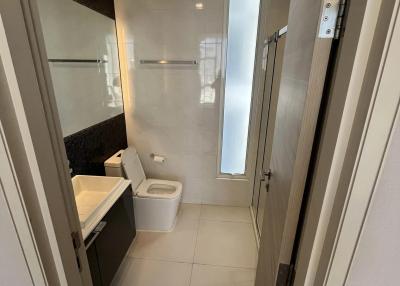 Modern bathroom interior with a white porcelain sink, toilet, and shower glass door