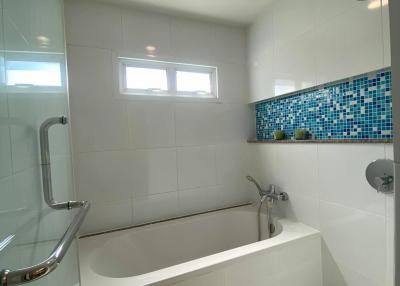 Modern bathroom with bathtub and blue mosaic tile detail