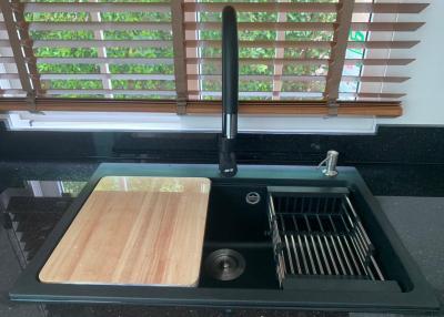 Modern kitchen sink with wooden chopping board and drying rack
