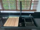 Modern kitchen sink with wooden chopping board and drying rack