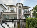 Elegant two-story house with stonework and iron fence