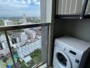 Compact laundry area with washing machine and city view