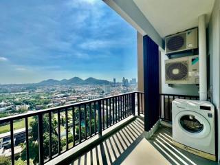 Spacious balcony with city and mountain views, featuring air conditioning units and a washing machine