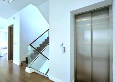 Modern hallway with wooden floors, an elevator, and staircase