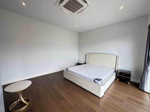 Spacious bedroom with wooden flooring, a large bed, and air conditioning unit