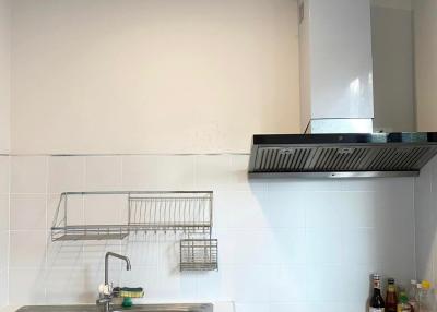 Compact kitchen with stainless steel sink, white tiling, and modern appliances