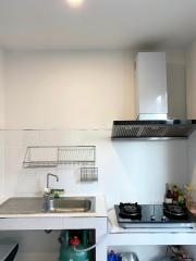 Compact kitchen with stainless steel sink, white tiling, and modern appliances