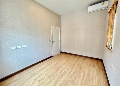 Spacious unfurnished bedroom with wooden flooring and air conditioning