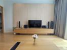 Spacious living room with modern entertainment setup and wooden flooring