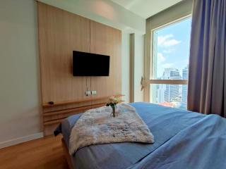 Modern bedroom with king-sized bed, wooden wall paneling, and city view