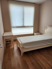 Cozy bedroom with large window and hardwood flooring