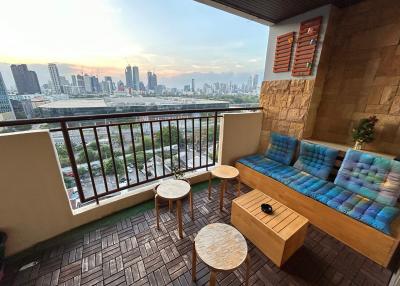 Cozy balcony with seating overlooking a city skyline at dusk