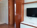 Modern bedroom with wooden cupboard, flat screen TV and wardrobe