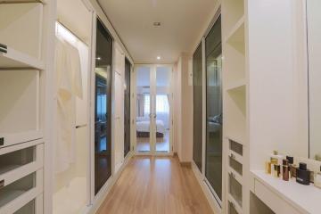 Modern hallway leading to a well-lit bedroom with glass doors