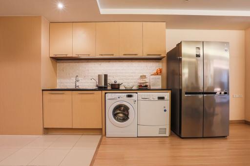 Modern kitchen with wood cabinets, stainless steel appliances, and integrated laundry machine