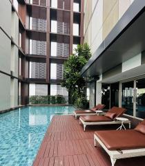 Contemporary poolside with lounging chairs and residential building facade