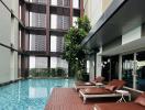 Contemporary poolside with lounging chairs and residential building facade