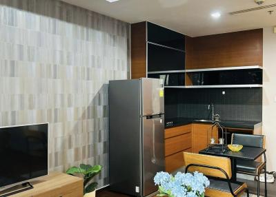 Modern living room with integrated kitchenette, featuring wooden furniture and elegant decor