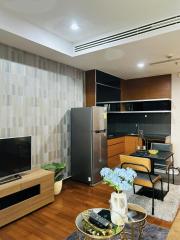 Modern living room with integrated kitchenette, featuring wooden furniture and elegant decor