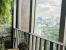 Cozy balcony with city view, featuring wooden circular table and potted plants