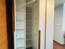 Compact storage closet with white shelves and wooden doors