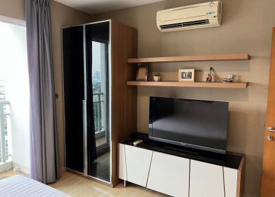 Modern bedroom with city view, TV, and air conditioner