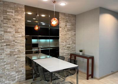 Modern dining area with stone accent wall and pendant lighting