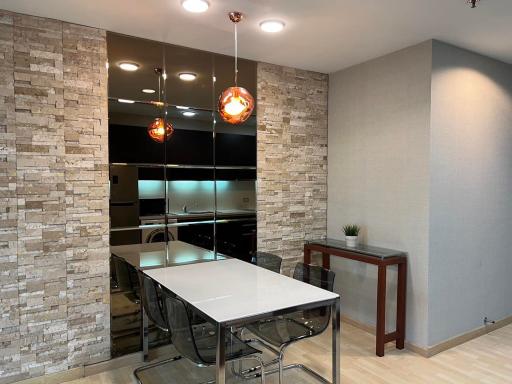 Modern dining area with stone accent wall and pendant lighting