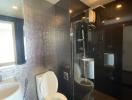 Modern bathroom with glass shower and glossy black tiles