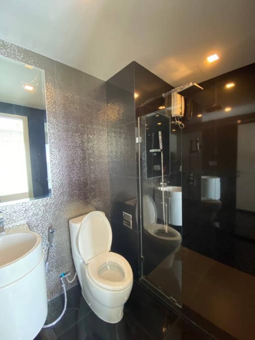 Modern bathroom with glass shower and glossy black tiles