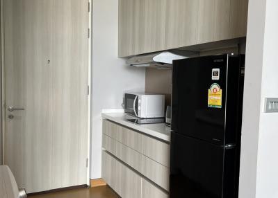 Modern kitchen with wooden cabinets and black fridge