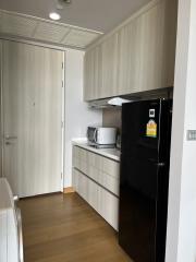 Modern kitchen with wooden cabinets and black fridge