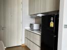 Modern kitchen with wooden cabinets and black fridge