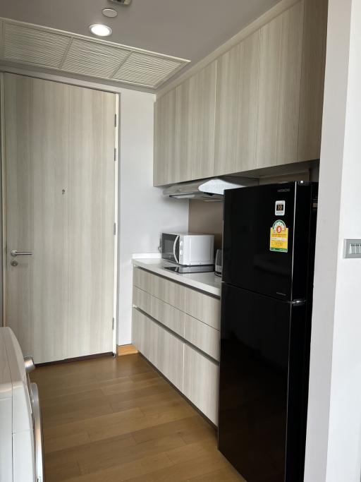 Modern kitchen with wooden cabinets and black fridge