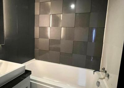 Modern bathroom with dark tiled walls and white bathtub