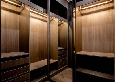 Modern walk-in wardrobe with LED lighting and wooden finishes