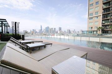 Modern rooftop swimming pool with city skyline view and lounge chairs