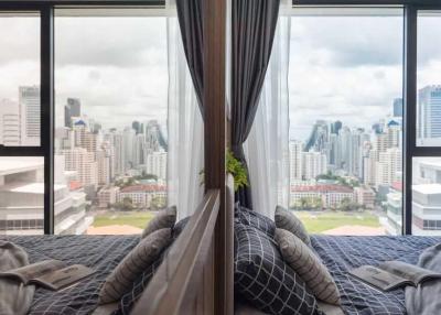 Modern bedroom with a panoramic city view through floor-to-ceiling windows